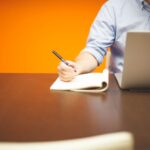 B2B professional writing a LinkedIn post on a laptop for a Thought Leader Ads campaign