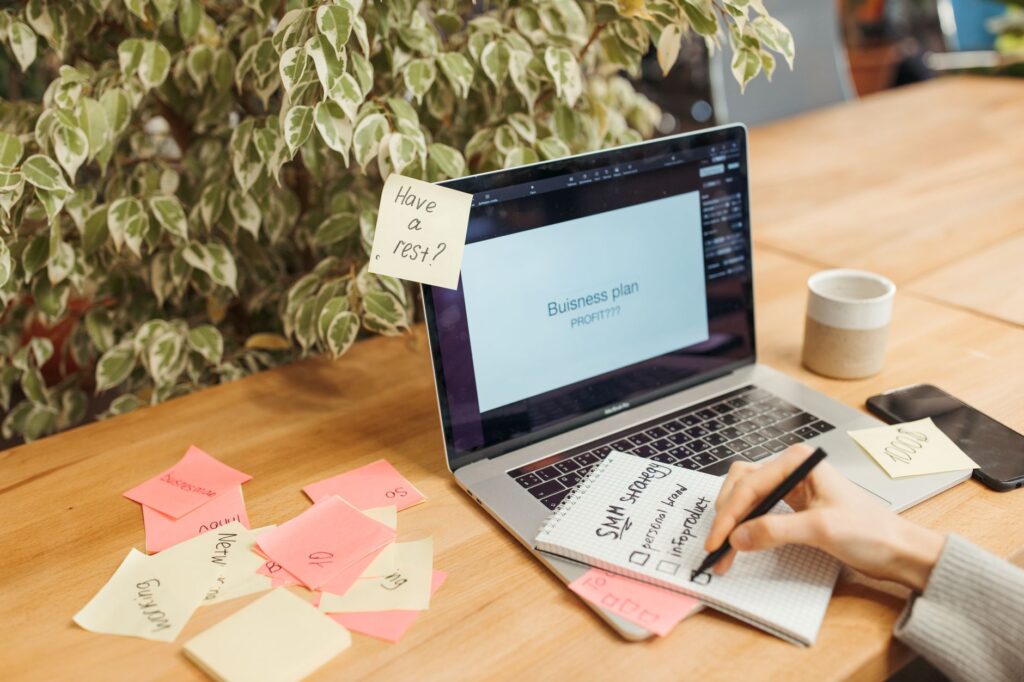 Marketer doing keyword research on a laptop with a notebook of keyword ideas