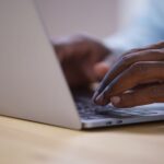 Marketer typing a question into an AI search bar on a laptop, illustrating AI search optimization