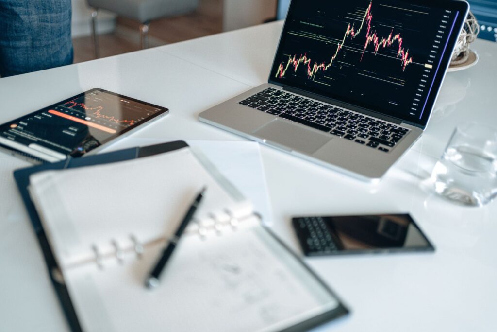 Notebook with digital marketing terms written beside a laptop showing analytics