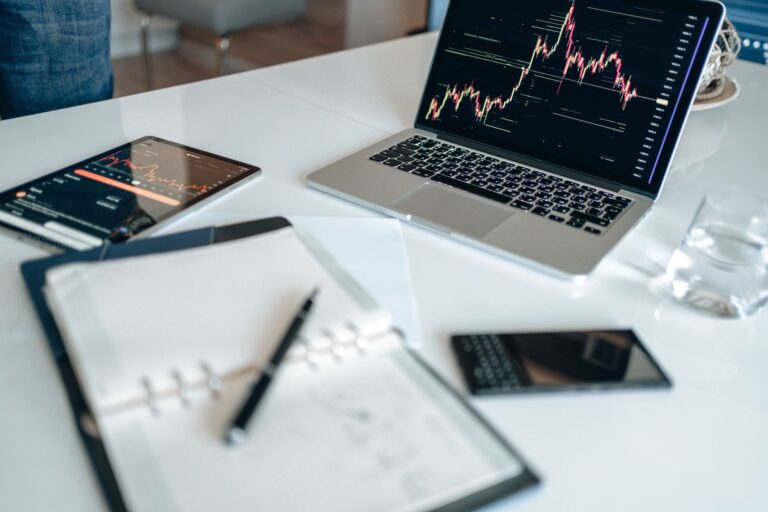 Notebook with digital marketing terms written beside a laptop showing analytics