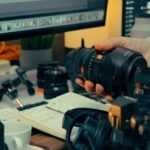 Video creator at a desk with a laptop and camera, setting up a YouTube A/B testing experiment for titles and thumbnails